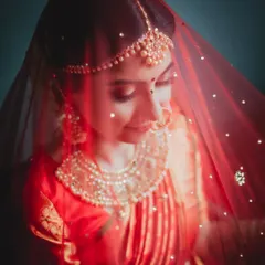The timeless beauty of a bride. This portrait uses soft, focused light to highlight the delicate details of her traditional attire, the rich color of her veil, and her serene expression.