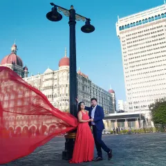A dramatic pre-wedding photo in front of the Taj Mahal Palace Hotel. The flowing red dress creates a stunning visual contrast against the iconic architecture, a signature style for our Mumbai shoots.