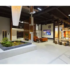 The interior of this commercial property is an inspiring experience. An indoor pond serves as a tranquil centerpiece in this double-height space, surrounded by natural wood and steel elements.