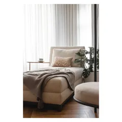 This cozy chaise lounge, placed by the window, is the perfect spot to unwind with a cup of tea and a good book.