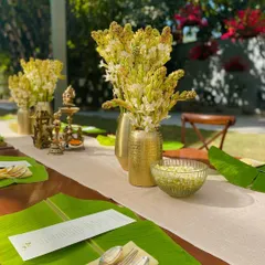 A closer look at the tablescape, featuring brass vases with tuberoses, elegant cutlery, and a custom menu on each banana leaf.