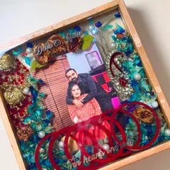 A unique preservation piece that includes a couple's photo, chuda (wedding bangles), and flowers from their varmala, all encased in a wooden resin frame.