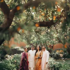 A family stands together on a garden path under the shade of an orange tree. This lifestyle portrait captures a formal moment in a relaxed, natural environment, showcasing the family's connection.