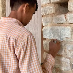 A craftsman carefully points the joints of the original stone wall. This traditional technique, using a lime-based mortar, is crucial for allowing the historic masonry to breathe and ensuring the long-term health of the structure.