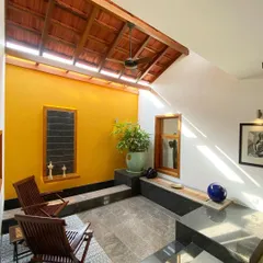 This semi-open seating area is illuminated by a long skylight set into the traditional tiled roof. The design allows for abundant natural light while protecting from the elements, creating a perfect transitional space.