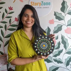 A participant proudly holding her finished dot mandala. The intricate patterns and bright colors make for a stunning piece of decor.