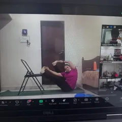 A student in our 5pm online class exploring a hip-opening variation using a chair for support. Our online classes are interactive and I guide you through each step.