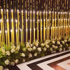 A stunning photo backdrop combining hanging beaded curtains and tall candle lamps. The black and white geometric floor adds a bold, modern touch to this glamorous setup.