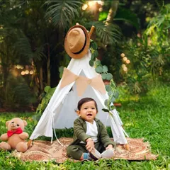 A little adventurer in the great outdoors. This adorable setup with a teepee and teddy bear is perfect for capturing the curious and imaginative spirit of a one-year-old.