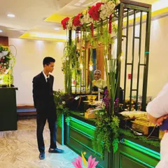 A guest admires the intricate details of the green and gold food station. The setup is designed to be interactive and visually engaging from all angles.