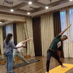 In our small batch classes, you get the guidance you deserve. Here, you can see one of our instructors providing personal alignment correction for Trikonasana (Triangle Pose) during a holistic yoga session. We keep our classes intimate so we can focus on your form and progress.
