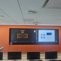 This conference room in Mumbai features functional acoustic wall panels in a bold orange fabric. They are installed around the display to reduce echo and improve sound quality during video calls.