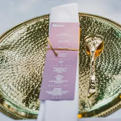 It's the little details that make an event special. This image shows a personalized menu tied with twine to a napkin, placed on a hammered golden thali, showcasing my attention to detail in table settings.