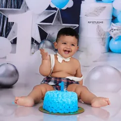 The pure joy of a first birthday is captured in this cake smash session. This little boy's infectious laugh and messy hands are the perfect representation of a milestone celebrated with fun and sweetness.
