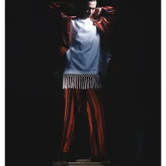 A full-body shot from the 'Silhouette' project, where the model is shrouded in darkness. The lighting carves out the shape of the striped suit and fringed top, focusing entirely on form.