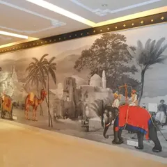 This large-scale mural depicts a vintage Indian procession with elephants and camels in a monochrome palette with color accents. It creates a powerful historical narrative along this long hallway, turning it into a gallery wall.