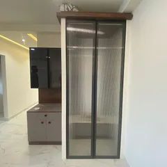 This custom wardrobe features sleek glass doors, providing a modern and stylish storage solution that also adds a sense of spaciousness to the room.
