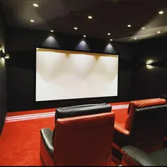A bold and classic cinema design featuring two-tone red and black leather recliners against a backdrop of dark walls and vibrant red carpeting. This traditional aesthetic delivers a nostalgic and high-impact movie-going experience at home.