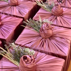 An example of our intricate fabric wrapping technique. This dusty rose satin fabric is meticulously pleated and folded into a central rose knot, accented with delicate dried flowers for a soft, romantic finish.