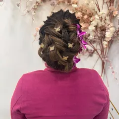A different angle of the beautiful braided updo, showing the intricate weaving and the placement of the butterfly clips and fresh flowers.