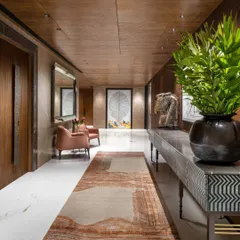An entrance lobby should be an immersive introduction to the home. In this Camellias apartment, we layered textures like ribbed wood veneers, Italian marble, and a hand-knotted rug to create a passage that is both grand in scale and warm in feeling, setting a tone of discovered richness.