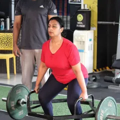 Form is everything. Here, I am guiding a client through a trap bar deadlift, ensuring her posture is correct to maximize strength gains and prevent injury. This is what personalized coaching looks like.