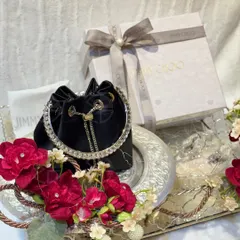 A luxury Jimmy Choo handbag presented on a mirrored tray, adorned with deep red florals. This is how I ensure even the most modern accessories are integrated into the trousseau with elegance and style.