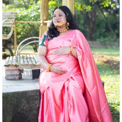 A quiet, contemplative moment during a traditional maternity session. The mom-to-be looks beautiful in her silk saree and ornate nose ring, seated on a bench in the park.