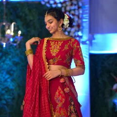 A vision of poise and grace. My client embodies elegance in an exquisite red suede lehenga, smiling joyfully at her celebration.