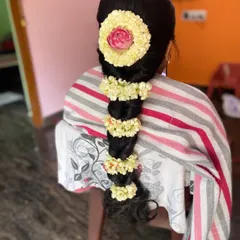 For this look, I created a neat, traditional braid and decorated it with jasmine strings and a central pink rose, adding a touch of color to the classic bridal hairstyle.