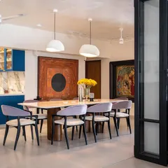 We believe in using color with confidence. In this open-plan Vile Parle apartment, a bold blue kitchen becomes the vibrant heart of the home, seamlessly connecting to the dining area. The custom dining table and chairs, along with striking artwork, create a space perfect for entertaining.