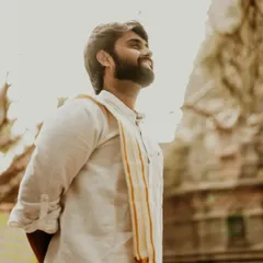 The groom looks on with a gentle smile, bathed in warm light against the backdrop of a historic temple. This individual portrait captures a sense of hopeful anticipation.