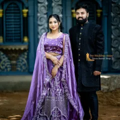 This couple is wearing a matching purple lehenga and a classic black sherwani. The dark, solid color of the sherwani allows the detailed embroidery and rich color of the lehenga to stand out, creating a balanced composition.