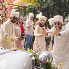 The Baraat is the heartbeat of the celebration. Here, the groom's friends dance with joy next to the beautifully decorated vintage wedding car.