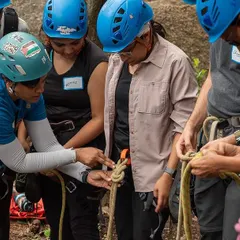 Safety is the foundation of everything we do. Here, one of our experienced female instructors guides a new climber through the fundamentals of knot tying, ensuring everyone feels confident and secure before they even touch the rock.