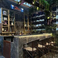 A full view of the stunning terrace bar we designed. The combination of a living wall, hanging plants, neon signs, and industrial-chic furniture creates a sophisticated and vibrant commercial-grade space.