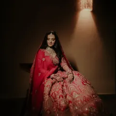 A full-length portrait showcasing the magnificent bridal lehenga. The single light source creates a dramatic, spotlight effect, making the bride the absolute center of attention.