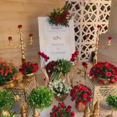 This is a welcome sign I created for an engagement ceremony, placed among an elaborate display of red roses, greenery, and golden candelabras.