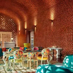 A vibrant dining space within Taj Devi Ratn, where I used a rich palette and custom-upholstered chairs to create a joyful, eclectic atmosphere. The textured copper walls and artistic furniture make every meal a feast for the eyes.