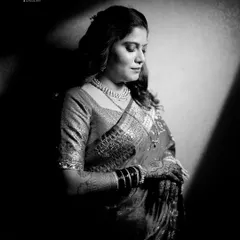 A dramatic black and white portrait of a bride in her reception saree. The play of light and shadow creates a timeless and artistic image.