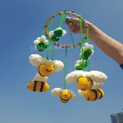 A whimsical honey bee-themed cradle hanging. It features happy little bees buzzing around fluffy white clouds, designed to gently spin and entertain your baby.