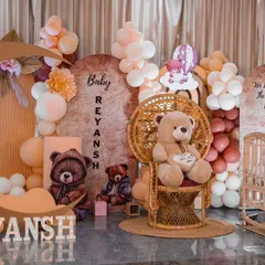 Another view of the teddy bear rice ceremony. The setup includes a crescent moon prop, a peacock chair for the baby, and multiple teddy bears, creating a full and adorable scene.