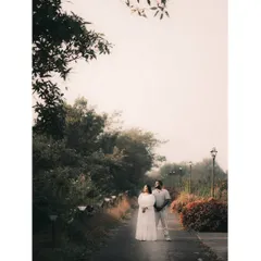 A wide shot of a couple standing on a misty path in Tamhini Ghat, capturing the scale and beauty of the natural surroundings.
