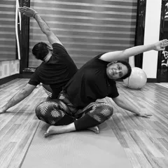 This black and white photo captures the beautiful symmetry of a partner side-stretch. This is a great way to improve flexibility in the side body while practicing with a friend or family member at home.