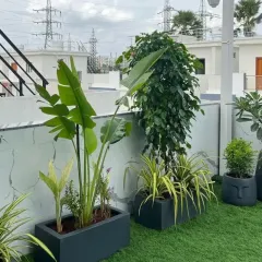A closer look at the details of a terrace garden, showing the texture of the artificial turf alongside carefully selected plants. The face-themed planters add a unique artistic touch to the modern green setup.