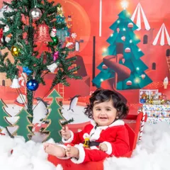 A sweet smile from Santa's cutest helper, sitting in her sleigh next to the Christmas tree.