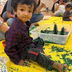 It's okay to get messy from head to toe. This little one is having the best time exploring a bin of taste-safe green goo at our Christmas party. This kind of full-body sensory experience is so important for development.