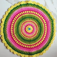 A top-down view of the Viola mandala, showing its perfectly circular shape and the variety of stitches used to create the pattern, including puff stitches and open lacework.