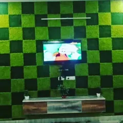 A media wall with a bold checkerboard pattern made from light and dark green artificial moss panels. This is a modern and playful way to frame a television.