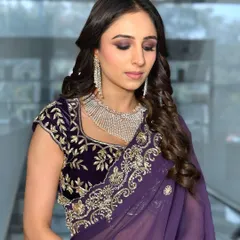A beautiful guest ready for a chowki event. The purple smokey eye and soft curls create an elegant and sophisticated look.